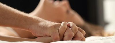 Couple ayant les mains enlacées couchés dans un lit