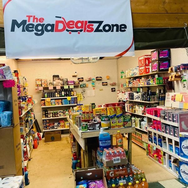 Inside The Mega Deals Zone grocery store with various products on shelves and tables.