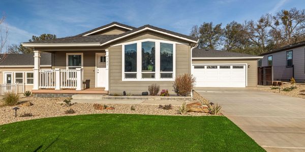 Modern single-story house with a green lawn and a spacious driveway.