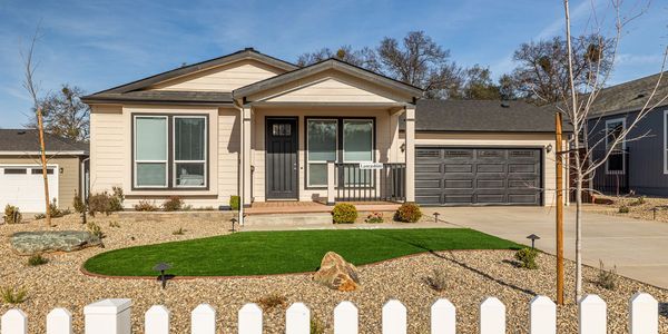 Modern single-story house with a small green lawn and gravel landscaping.