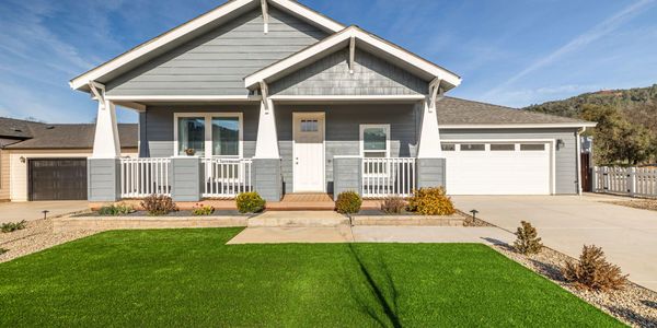 A modern gray house with a well-maintained lawn and white porch railings.