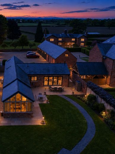 A countryside home complex illuminated at dusk with a vibrant sunset.