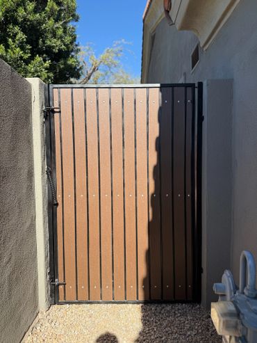 A closed wooden gate casting a shadow on one side between two walls.