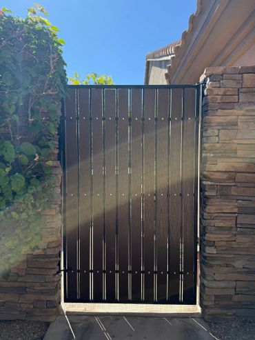 Wooden gate between stone walls with sunlight and clear blue sky.