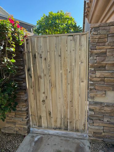 Wooden gate between stone walls with plants around.