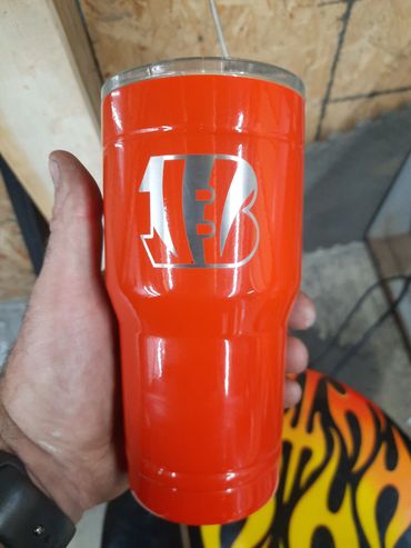 Hand holding a bright red insulated tumbler with a white house logo.