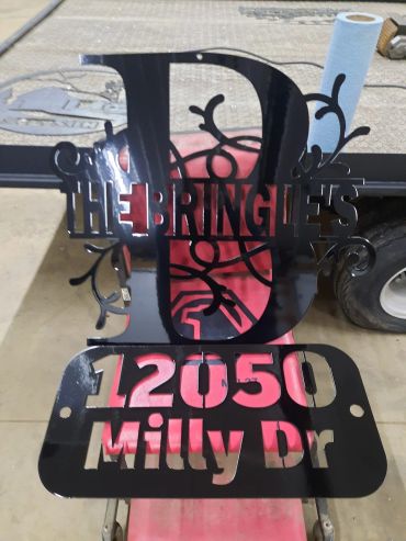 Decorative black metal sign displaying 'The Bringles' and address '12050 Milly Dr'.