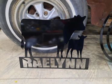 Metal silhouette of a cow and calf with 'RAELYNN' text below.