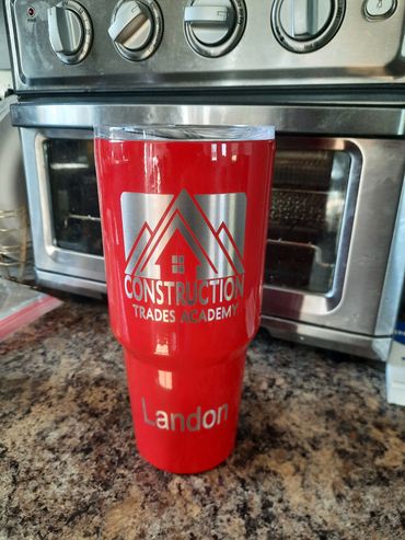 Red cup with Construction Trades Academy logo on kitchen counter.