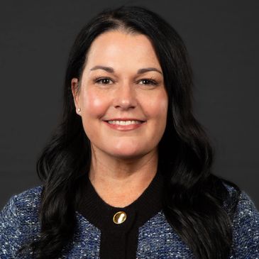 Smiling woman with long black hair against a dark background.