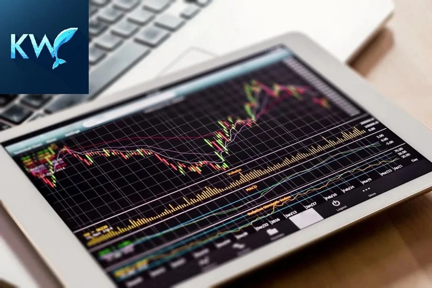 Tablet displaying a financial stock chart with fluctuating data lines and a laptop keyboard in the background.