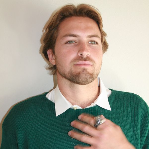 Man with green sweater and hand on chest posing.