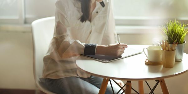 Lady sitting at table using an iPad.