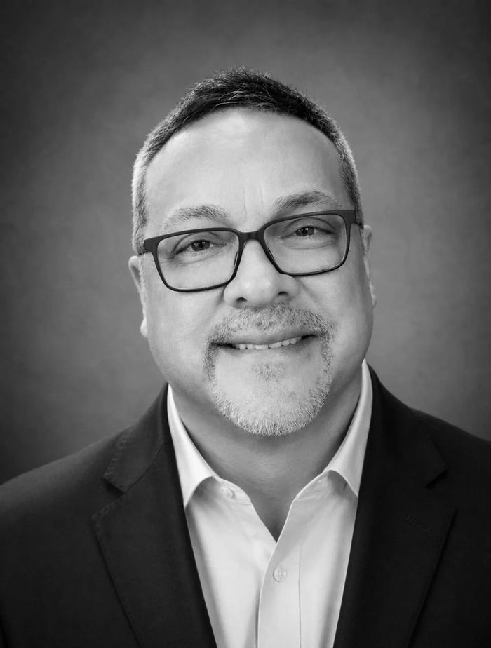 Black and white portrait of a middle-aged man with glasses and a slight smile.