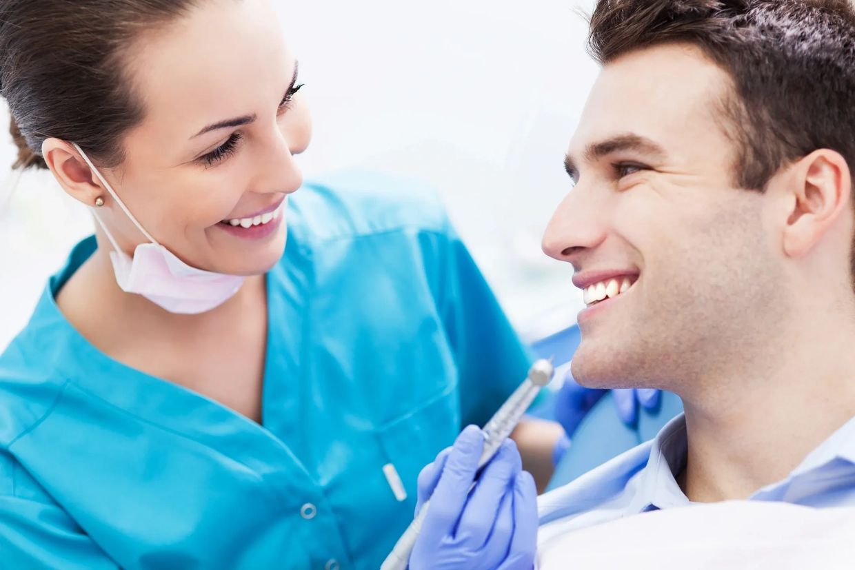 Smiling dentist preparing syringe for male patient.