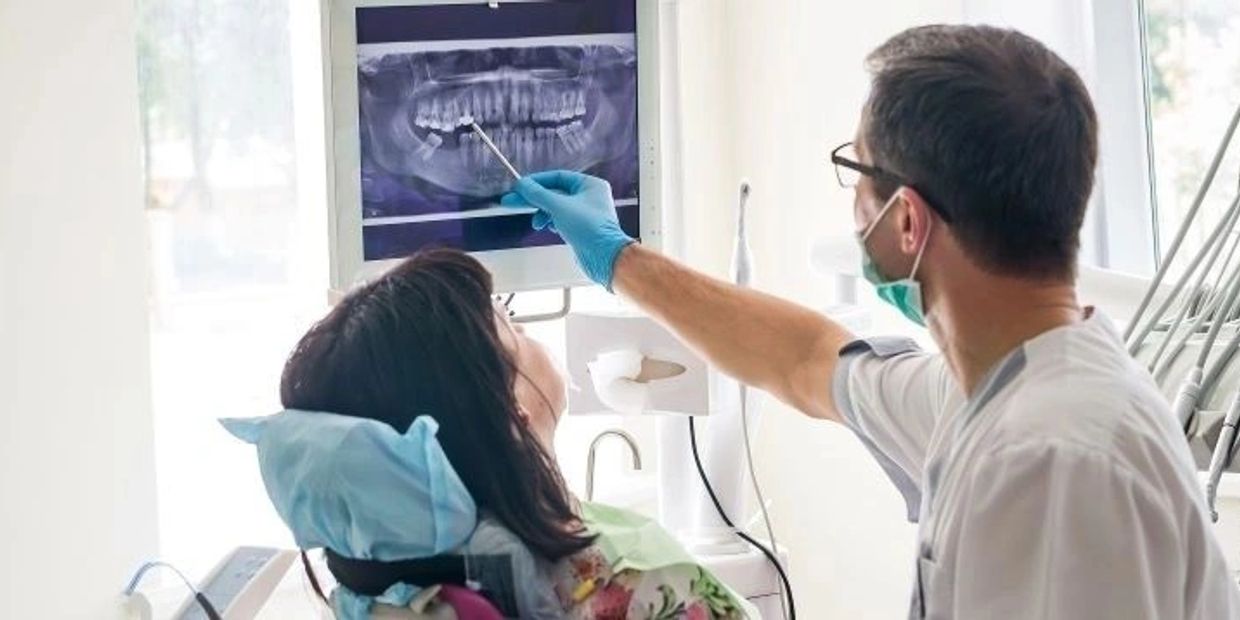 Dentist showing dental X-ray to patient in clinic.