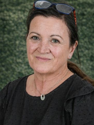 Middle-aged woman smiling gently with glasses on her head.