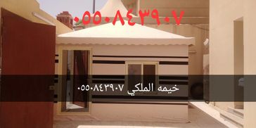 خيمة ملكي بيضاء مع خطوط سوداء وأبواب ونوافذ في فناء خارجي.