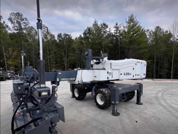 A large white industrial machine with four wheels in an outdoor area.