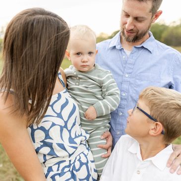 A family of four outdoors, sharing a tender moment.