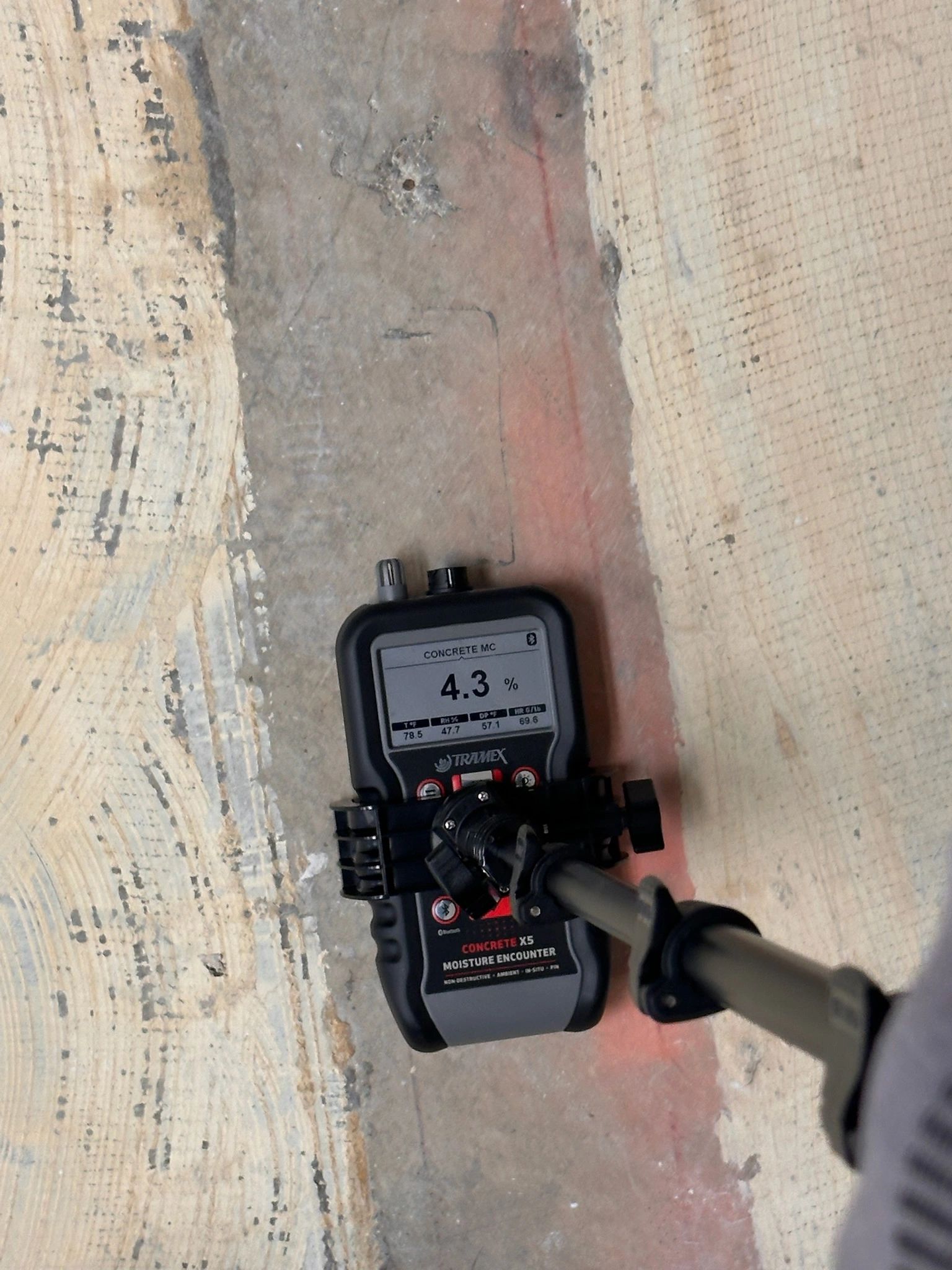 Moisture meter showing 4.3% reading on concrete floor.