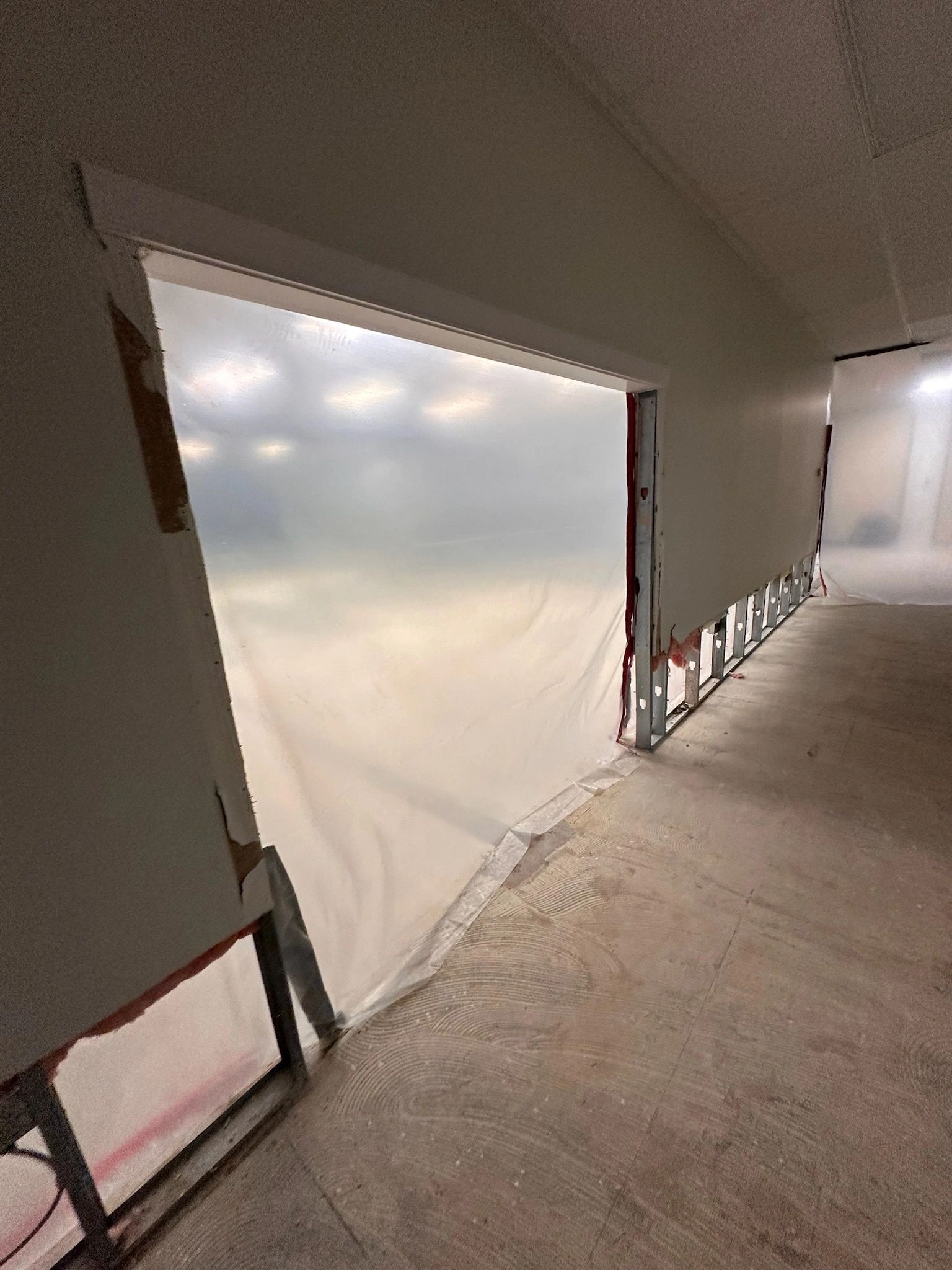 Hallway under construction with plastic sheeting on walls.
