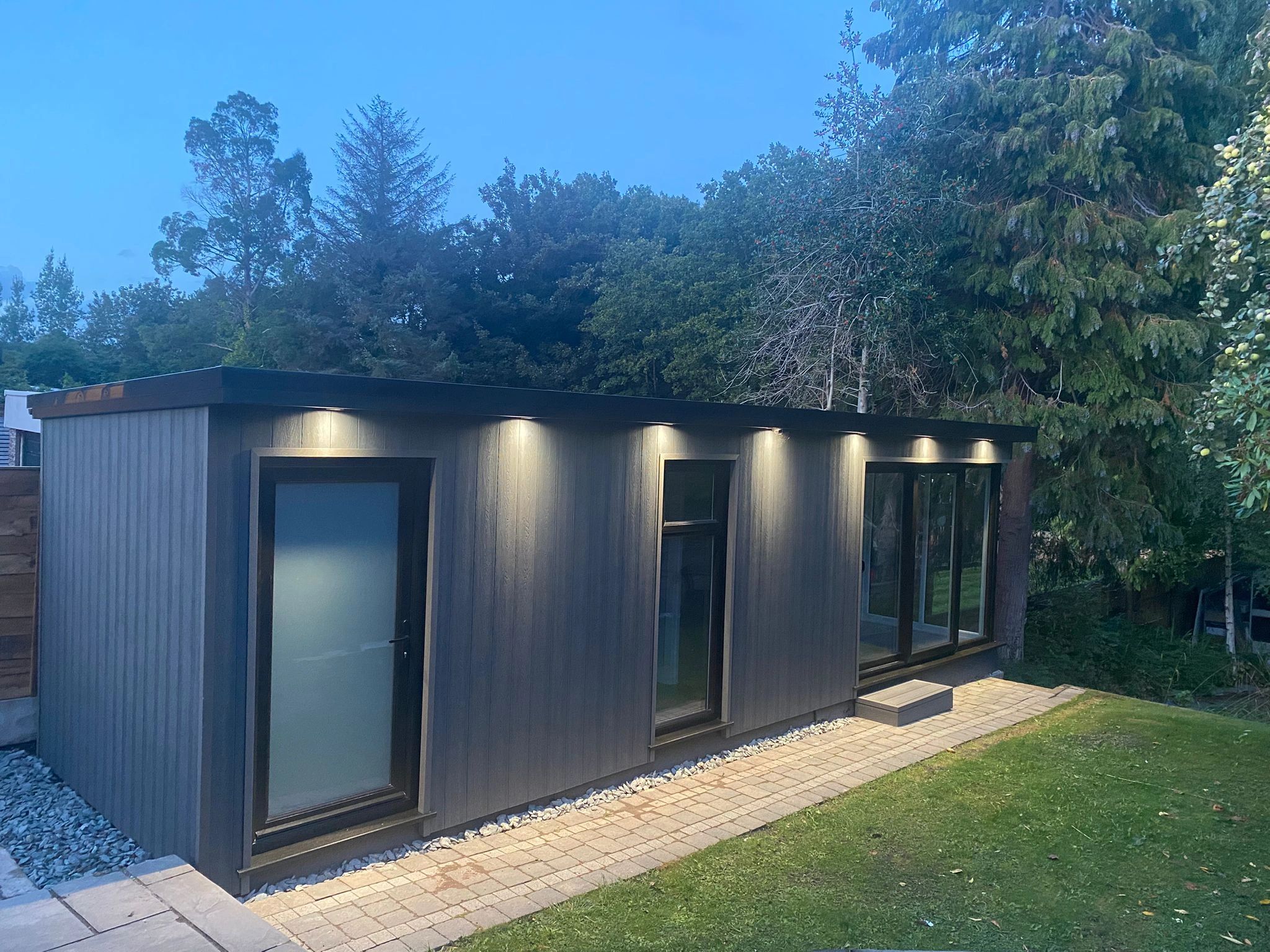 Exterior of a composite garden office at night. 