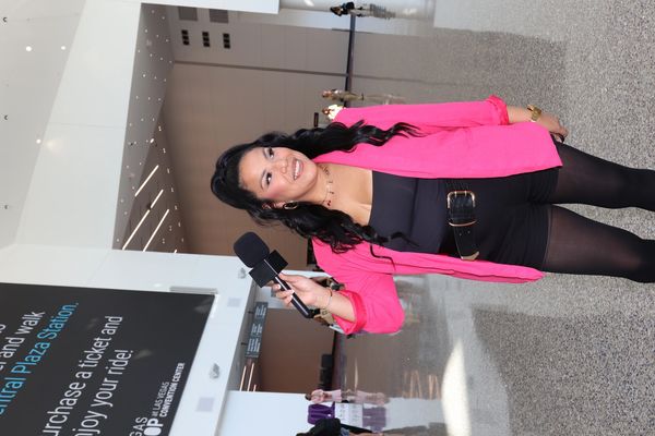 Woman in pink blazer holding a microphone indoors.
