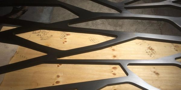 Intricate black metal design over wooden floor with footprints.