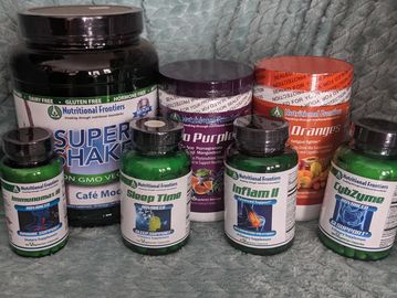 Nutritional Frontiers dietary supplements and protein shake containers on a soft blue surface.