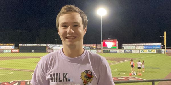 Smiling young man at a baseball field during night.