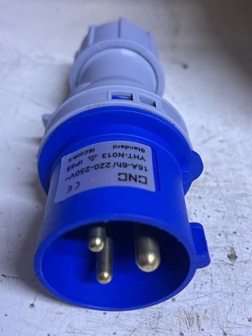 Blue industrial electrical plug with three metal prongs.