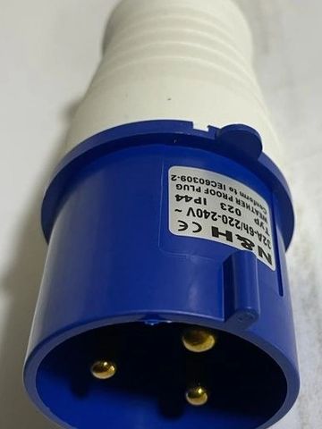 Close-up of a blue industrial electrical plug with three gold pins.