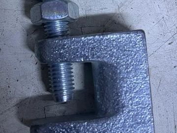 Close-up of a metallic clamp with a bolt on a textured surface.