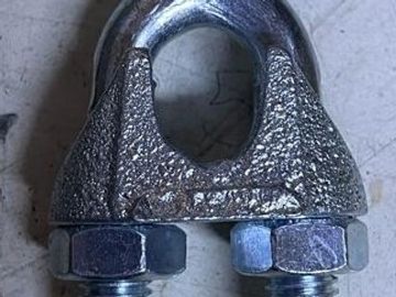 Close-up of a metal wire rope clip with two bolts.