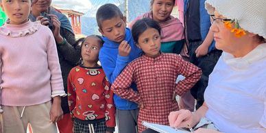 A woman sketching while a group of children and a woman watch attentively outdoors.