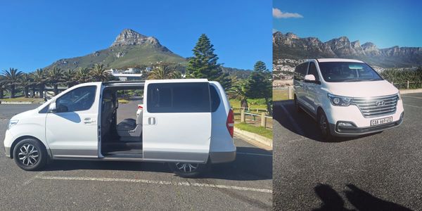 White Hyundai van parked with sliding door open, mountain backdrop.