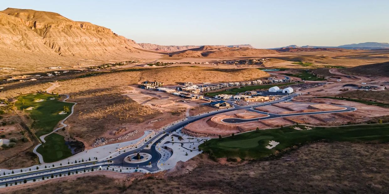 Aerial view of a desert neighborhood with winding roads and green golf course patches.
