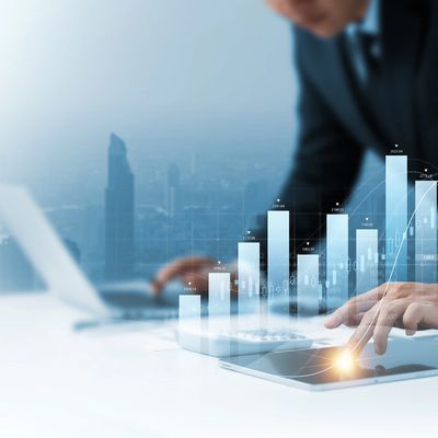 Businessperson analyzing rising financial data on digital tablet with cityscape background.