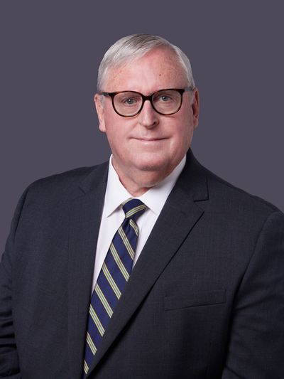 Professional elderly man in suit with glasses and striped tie.