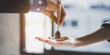 Handing over house keys representing home ownership or real estate transaction.