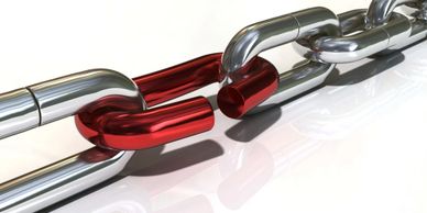A close-up of a metallic chain with a broken red link.