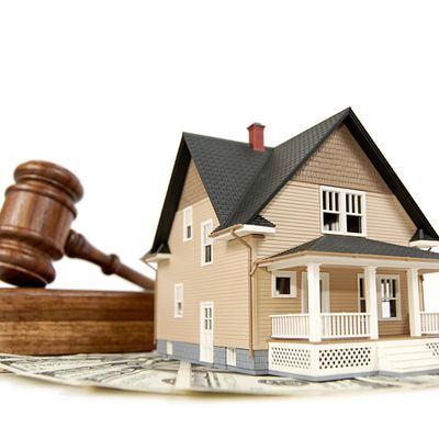 A model house with a gavel and dollar bills symbolizing real estate law or property auction.
