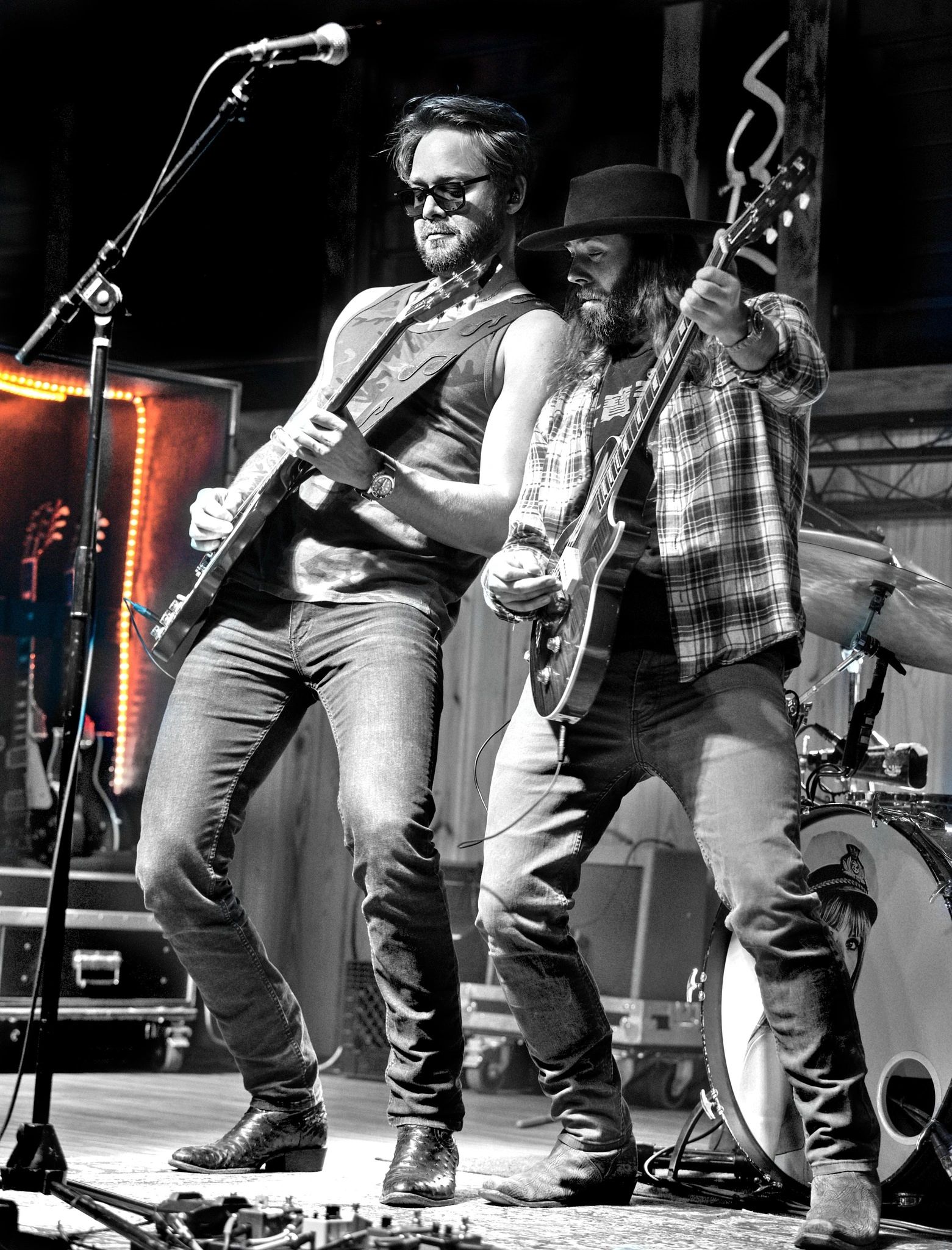 Two musicians passionately playing electric guitars on stage during a live performance.
