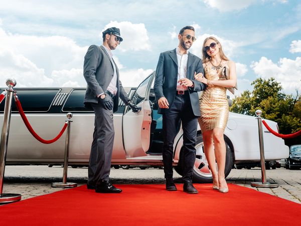 Two celebrities walking on a red carpet from a limousine