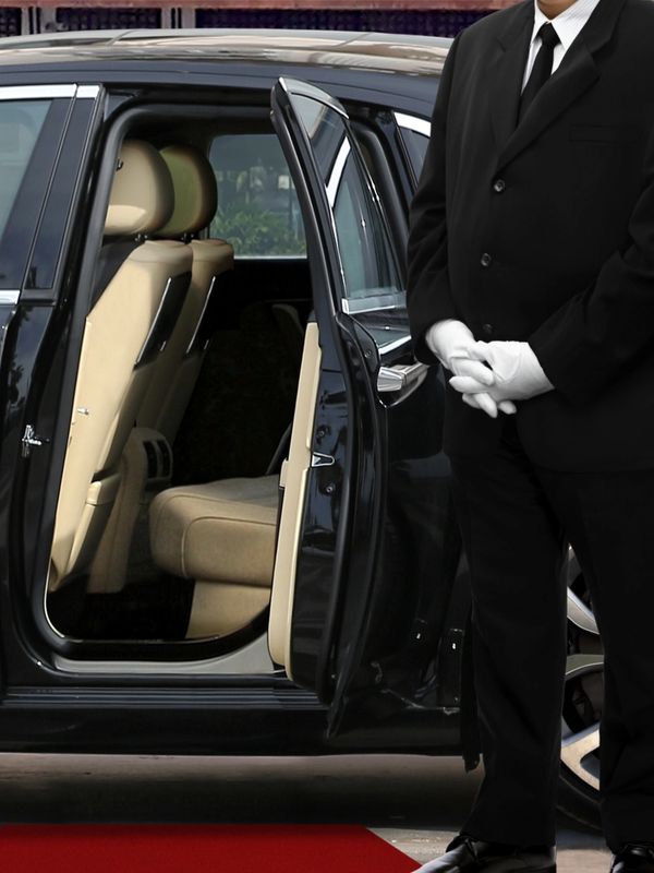 A limousine driver staying in front of the limousine