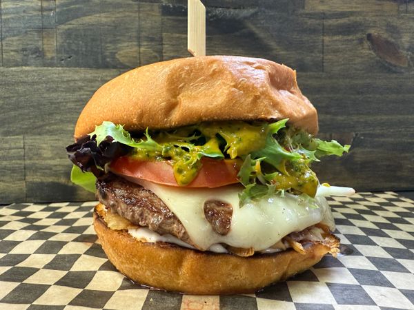 A juicy cheeseburger with lettuce, tomato, and sauce on a toasted bun.