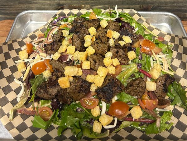 Grilled steak salad with mixed greens, cherry tomatoes, and croutons.