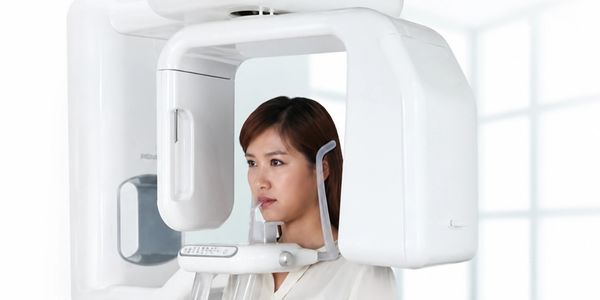 Woman undergoing dental X-ray with panoramic imaging machine.