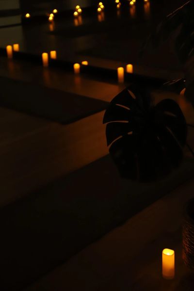 Dimly lit room with candles and yoga mats creating a peaceful ambiance.